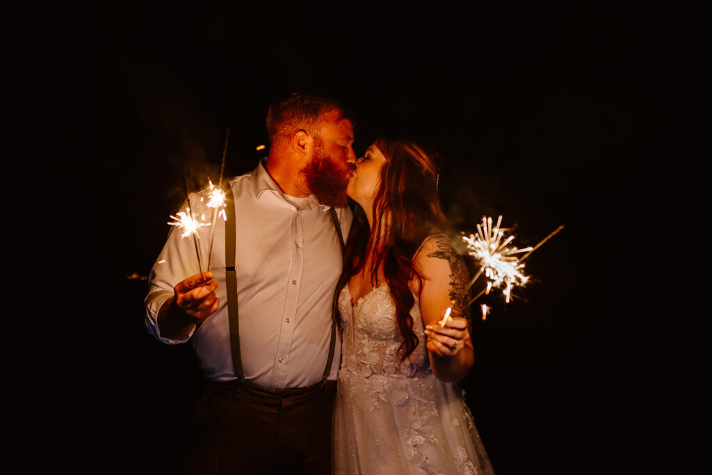 the wedding couple with sparklers at their fall wedding celebration