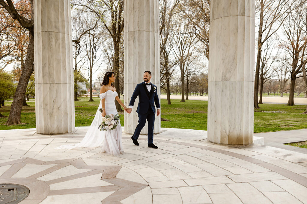 the wedding couple walking through the DC War Memorial