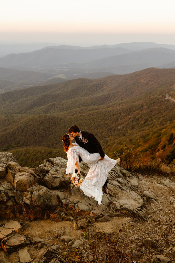 the wedding couple kissing on top of the mountain