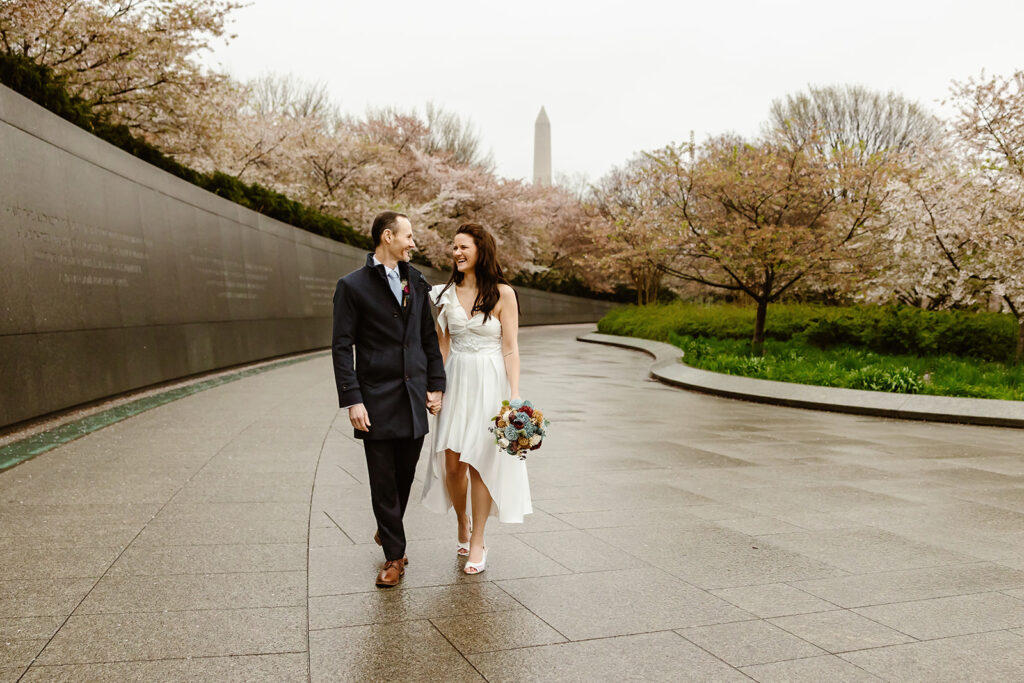 the wedding couple walking in DC by the spring cherry blossoms