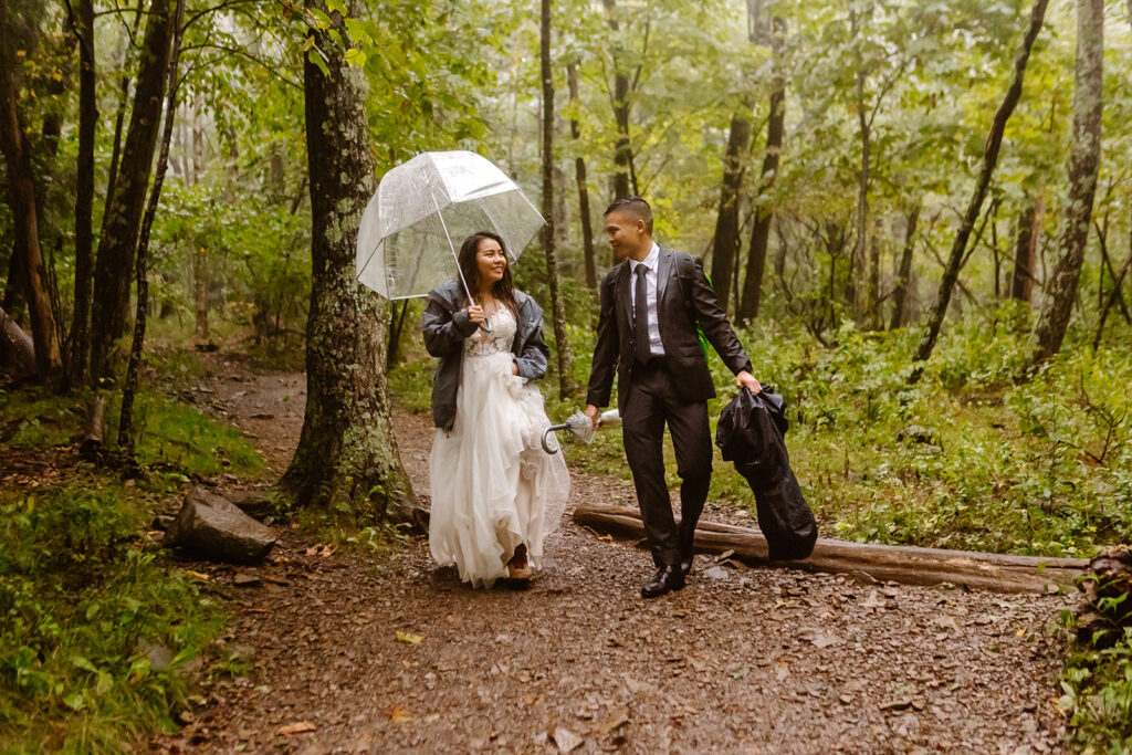 the wedding couple walking through the rain with their bad weather gear