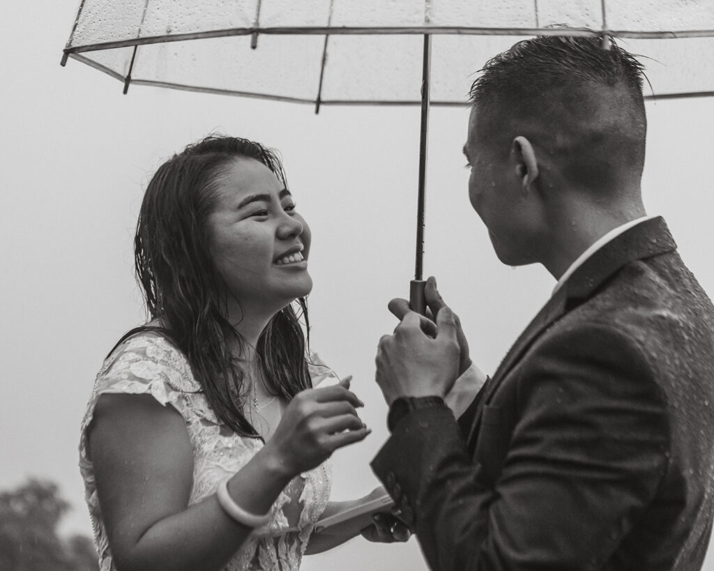 the wedding couple smiling together in the rain during their elopement ceremony 