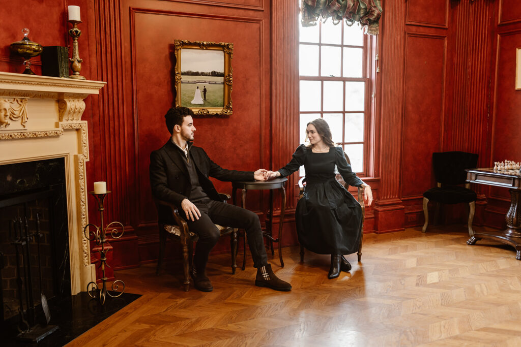 the engaged couple sitting in the red room at the Great Marsh Estate