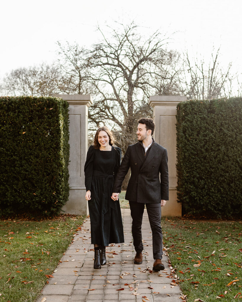 the engaged couple walking together through the garden