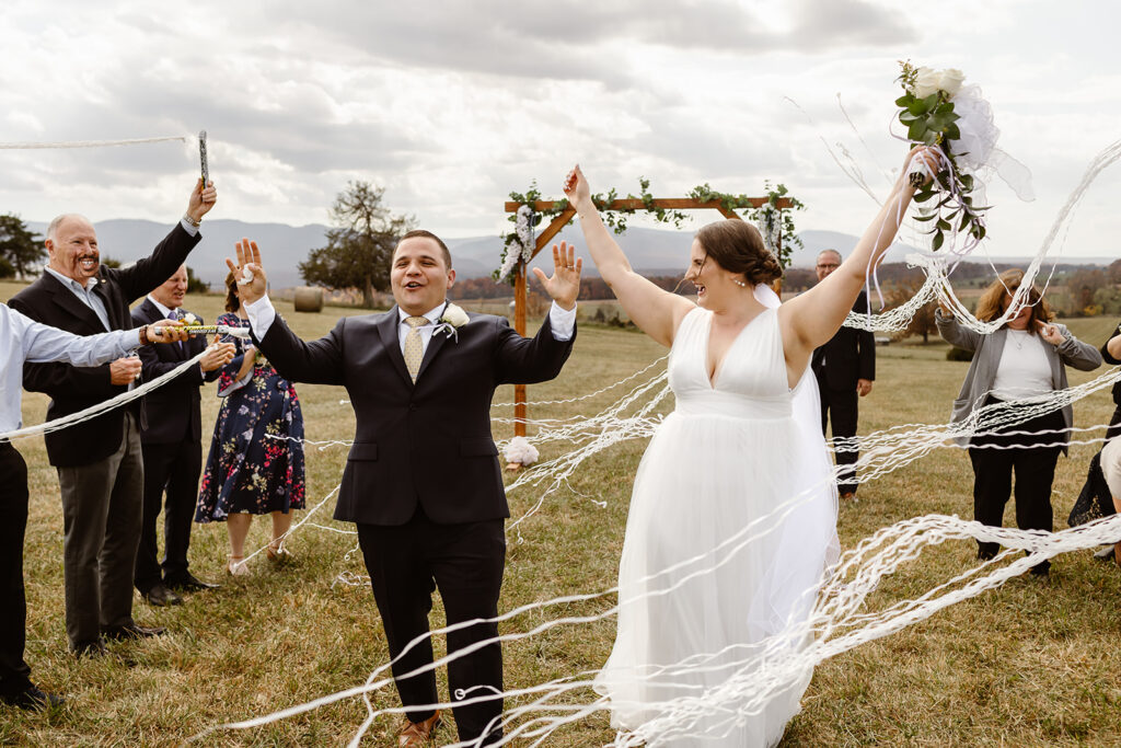 the wedding couple celebrating their wedding with streamers as they exit the aisle