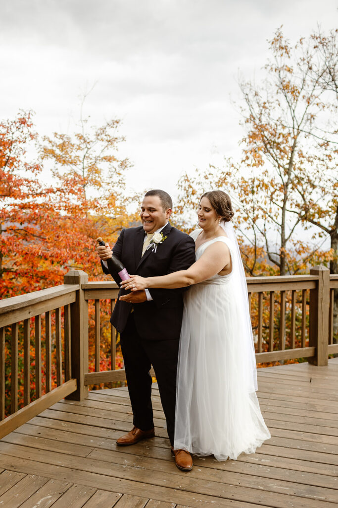 the wedding couple popping a bottle of champagne for their fall elopement