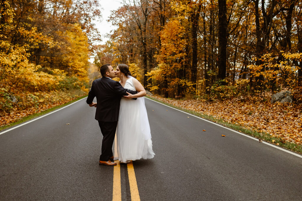 the wedding couple walking together in the fall leaves