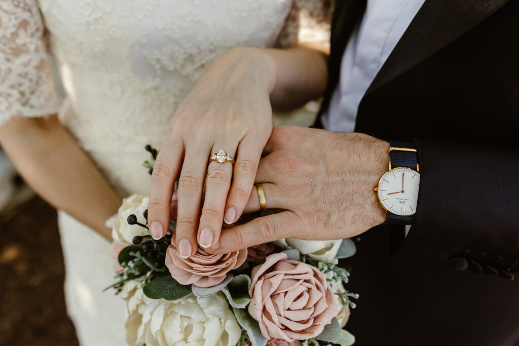 the wedding couples wedding rings on top of the wedding florals