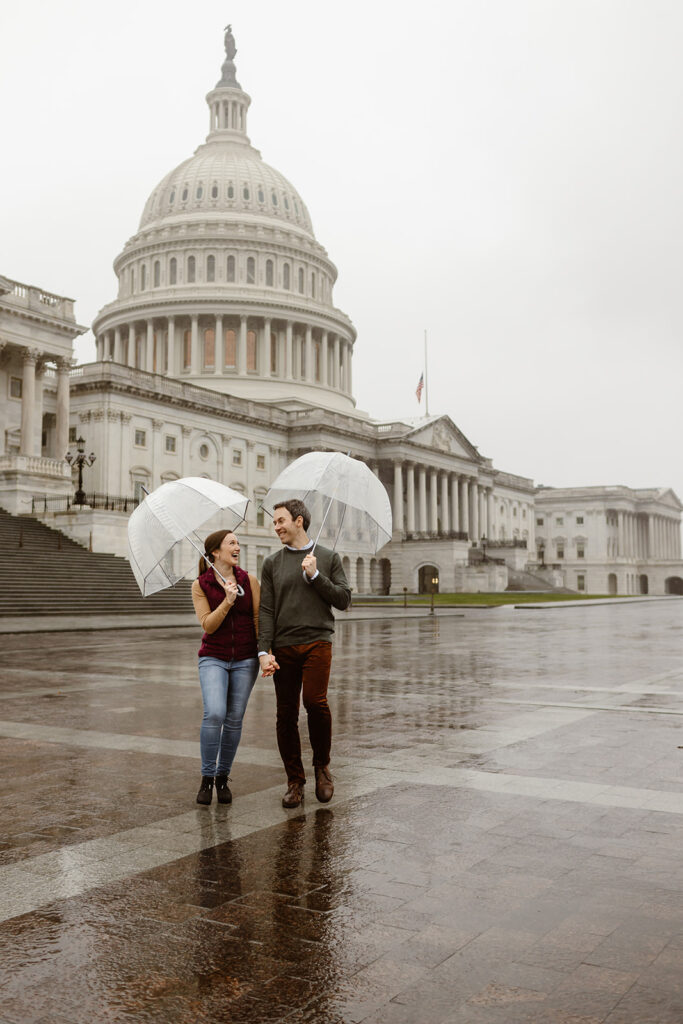 the engagement couple walking through Washington DC with clear umbrellas during their DC engagement pictures