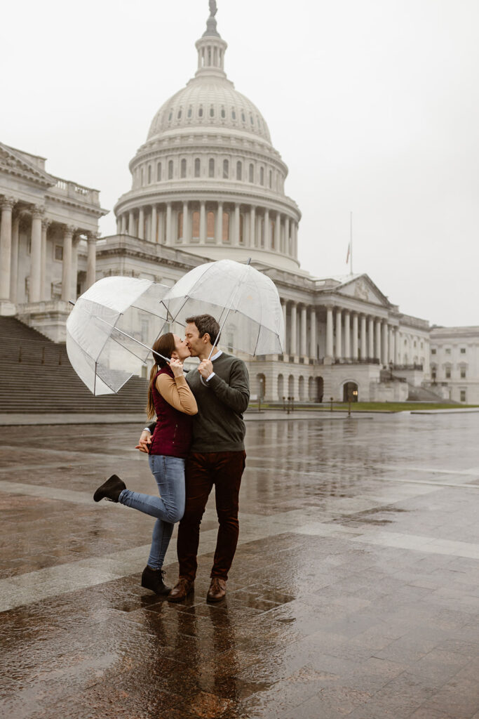 the engagement couple kissing in the rain with clear umbrellas in Washington DC