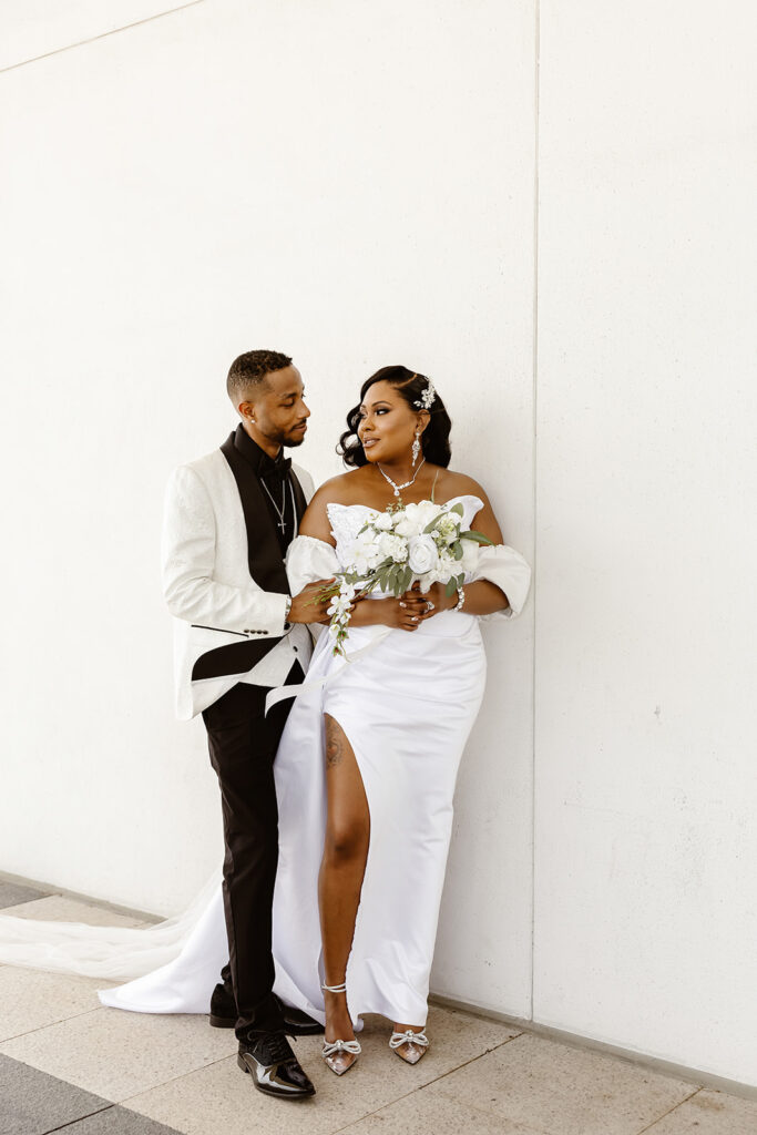 the wedding couple by a white wall for elopement photos