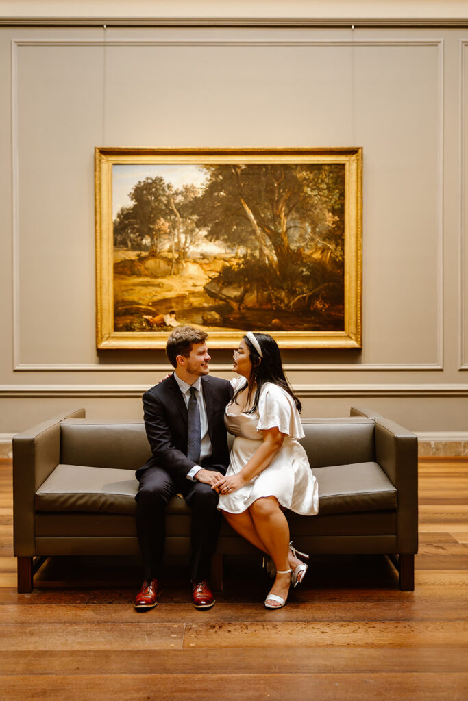 the wedding couple sitting on the couches by the art