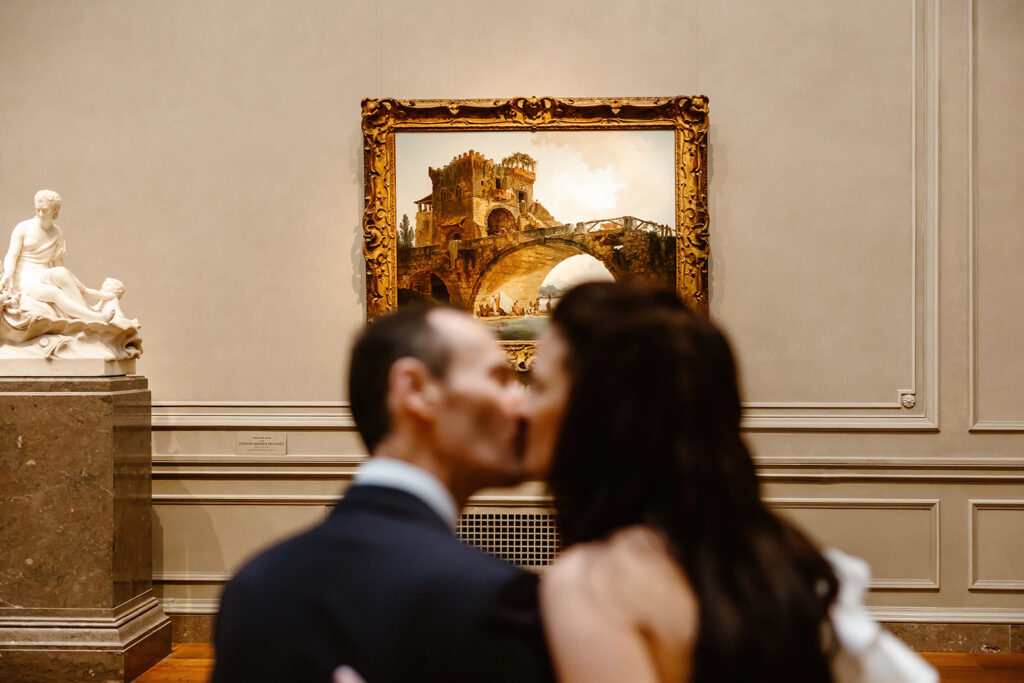 the wedding couple kissing in front of a painting at the DC art museum