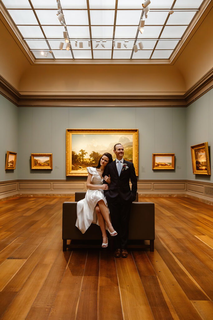 the elopement couple sitting on the couch in the art museum