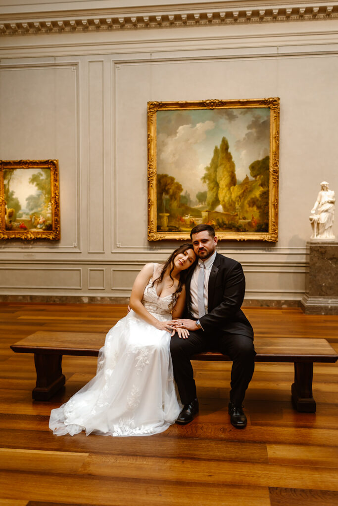 the wedding couple sitting looking at art 