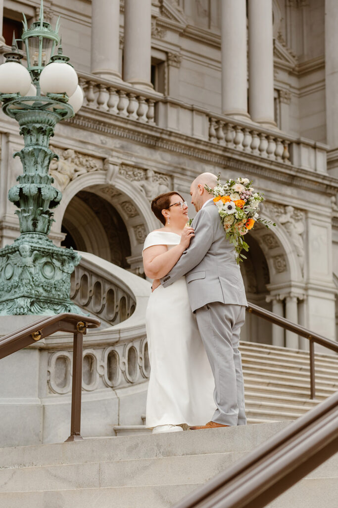 the wedding couple leaning in for a kiss on the steps of the Library of Congress