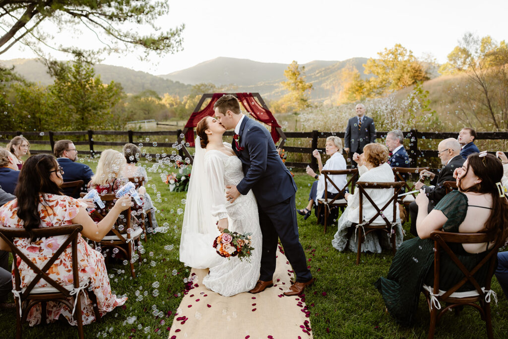 the wedding couple kissing down the aisle after their intimate ceremony