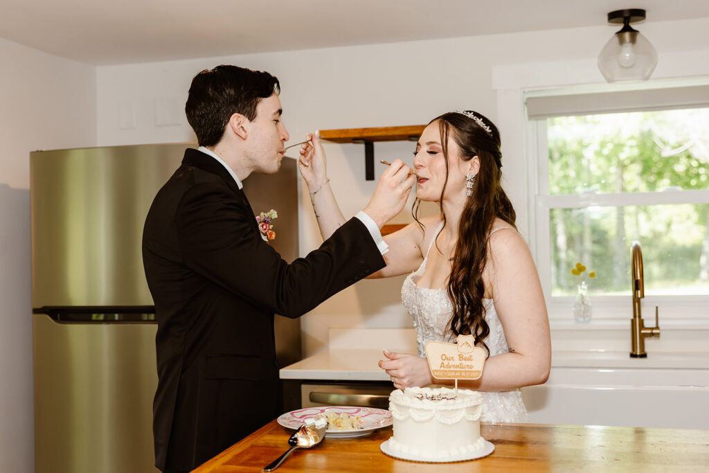 bride and groom cutting cake in a small kitchen during their vrbo wedding in shenandoah national park