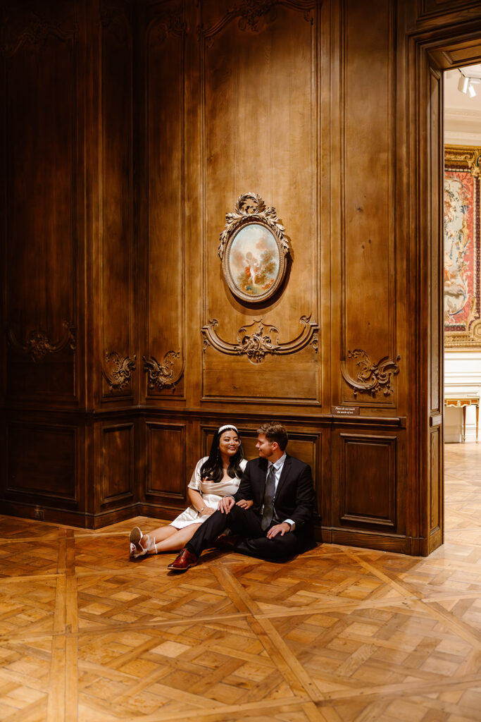 the couple sitting on the ground for engagement photos in a historic vintage room at the art museum
