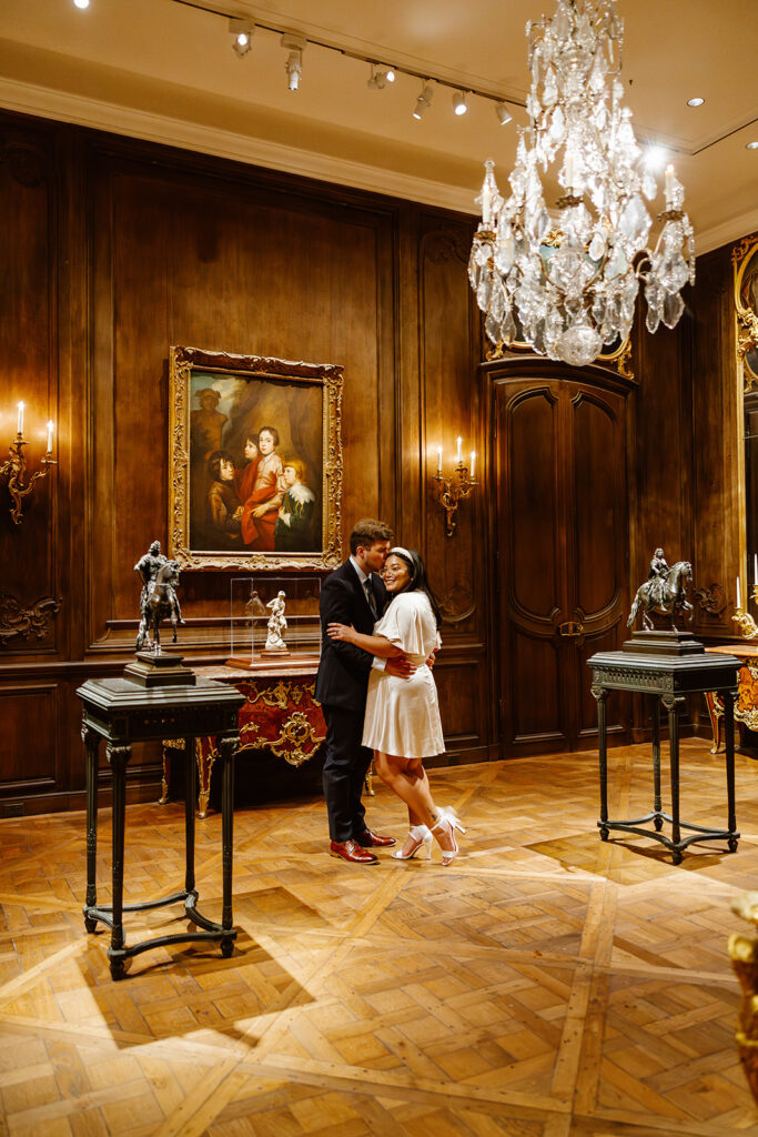 the couple sitting on the ground for engagement photos in a historic vintage room at the art museum
