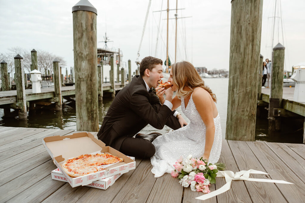 bride and groom sharing a pizza at the waterfront in annapolis