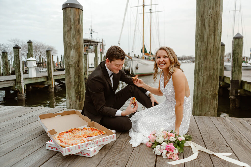 bride and groom sharing a pizza at the waterfront in annapolis