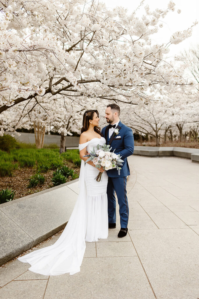 bride and groom posing in front of cherry blossoms in washington dc