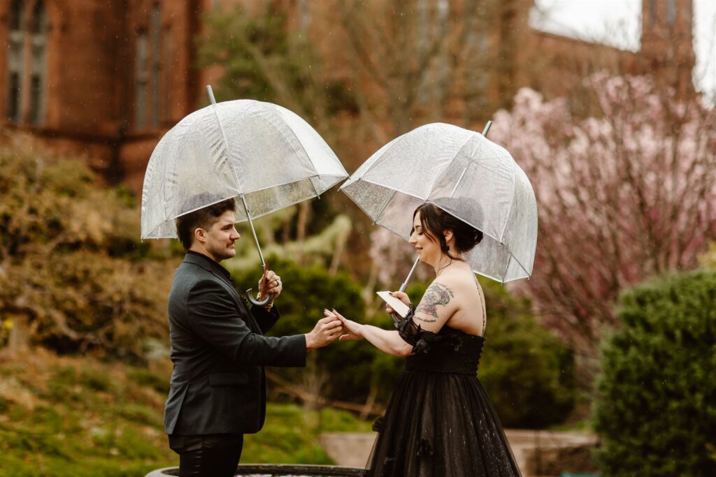 rainy vow exchange in Smithsonian gardens during a dc elopement, bride and groom holding clear umbrellas