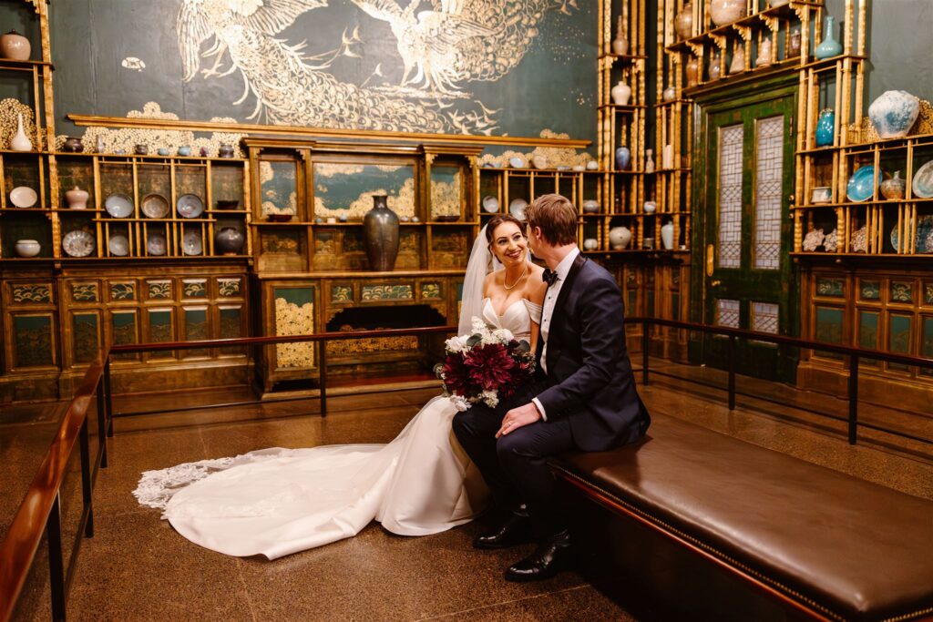 bride and groom sitting in a room with vintage paintings at the freer gallery of art