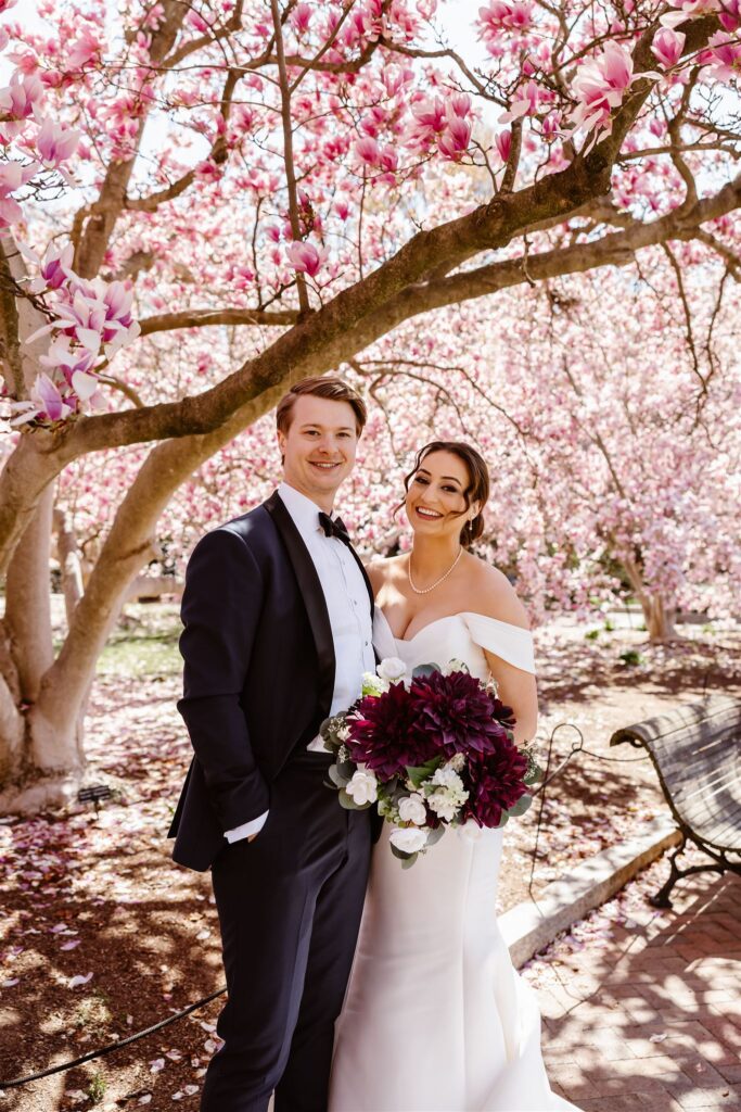 bride and groom with pink blossoms in the background at the smithsonian castle garden