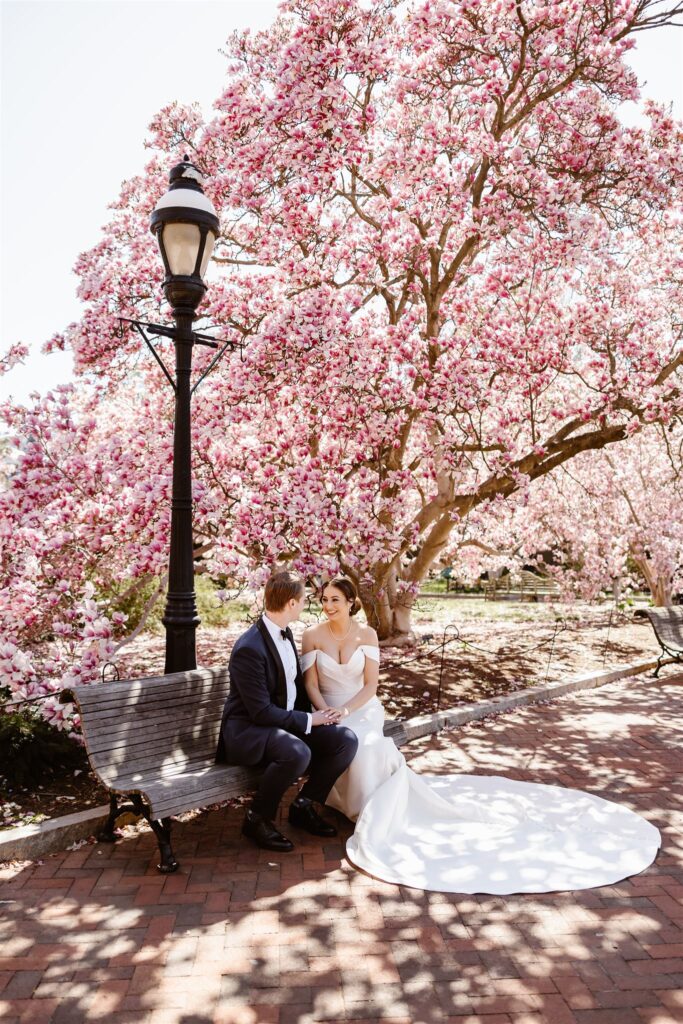 bride and groom with pink blossoms in the background at the smithsonian castle garden