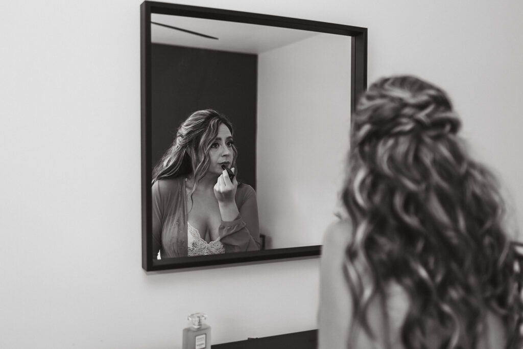 bride putting on lipstick in front of a mirror