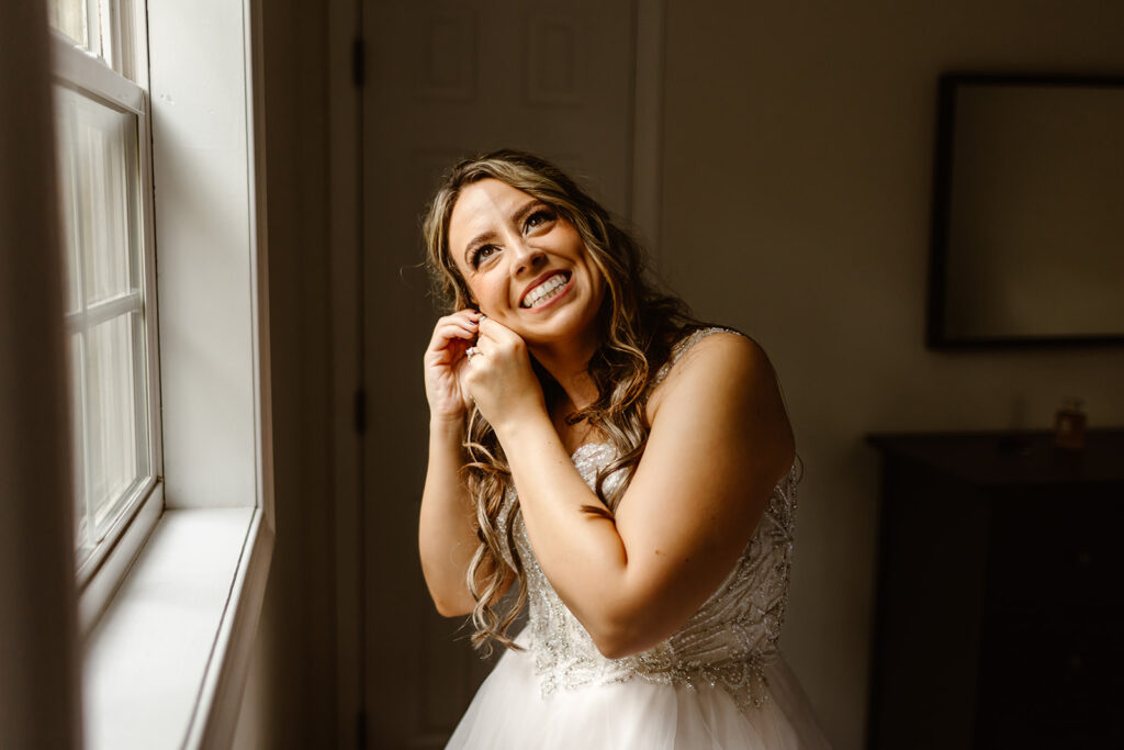 bride getting ready next to a window at the airbnb
