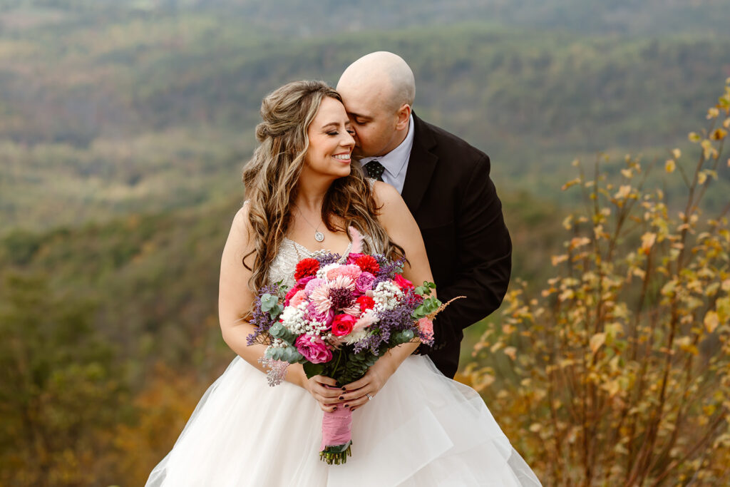 bride and groom hugging on foggy overlook at Stony Man summit in Shenandoah during their Shenandoah National Park elopement in October with fall foliage in the backdrop
