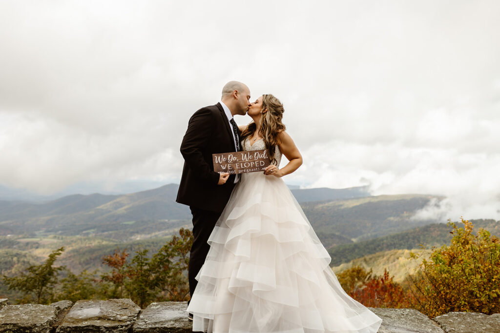 bride and groom holding their custom just eloped sign surrounded by fall foliage during their shenandoah elopement