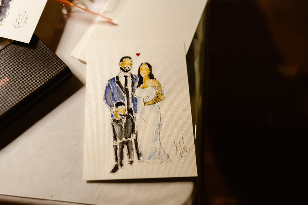 artist painting the wedding couple in water color