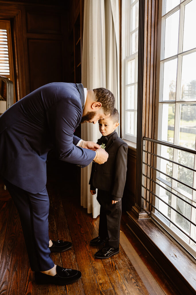 groom helping his little boy get ready for the wedding day