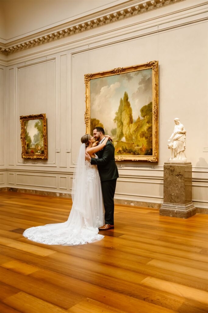 bride and groom kissing in front of paintings at the national gallery of art