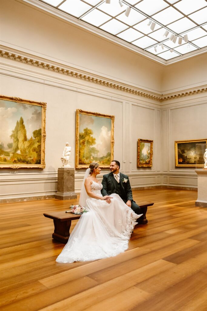 bride and groom sitting on a bench inside the national gallery of art