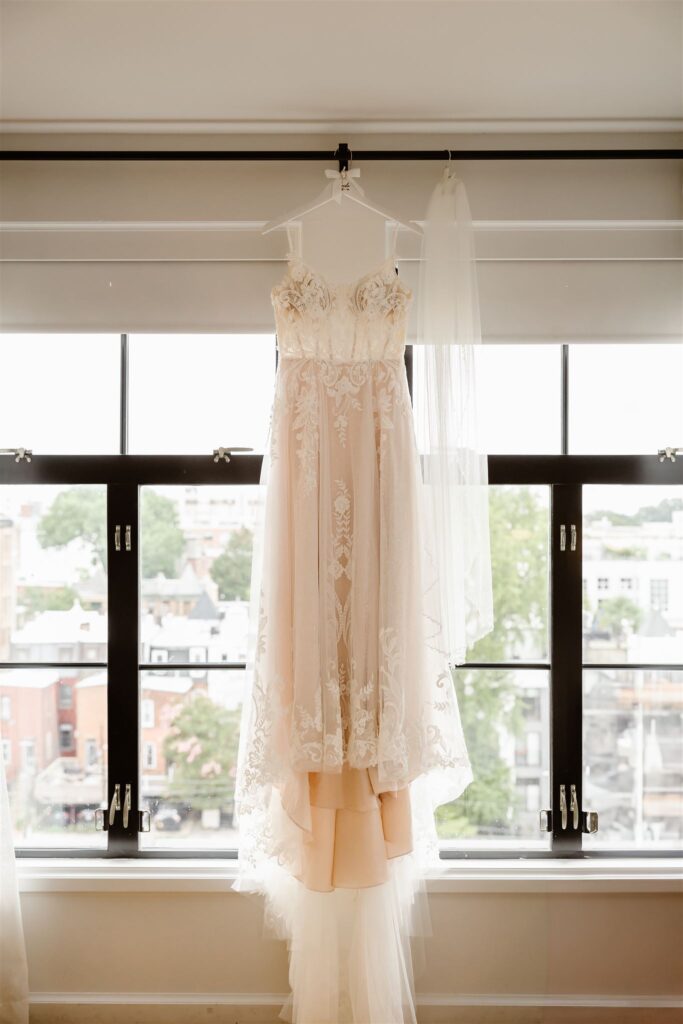 wedding dress hanging from the window at the hotel room