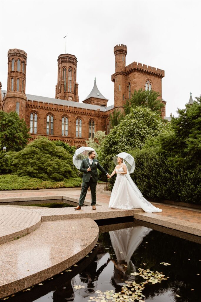 sweet bride and groom under clear umbrellas during rainy moments at the smithsonian castle garden