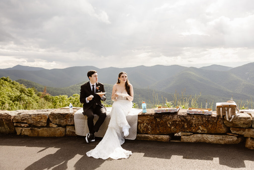 bride and groom sharing pizza in shenandoah national park for a post elopement reception celebration
