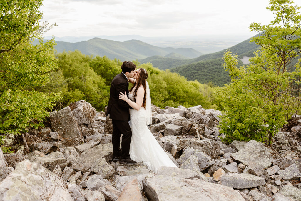 elopement couple kissing at a mountain overlook during their summer elopement in shenandoah