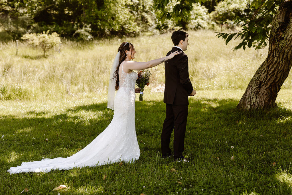 bride and groom elopement first look in a lush green field