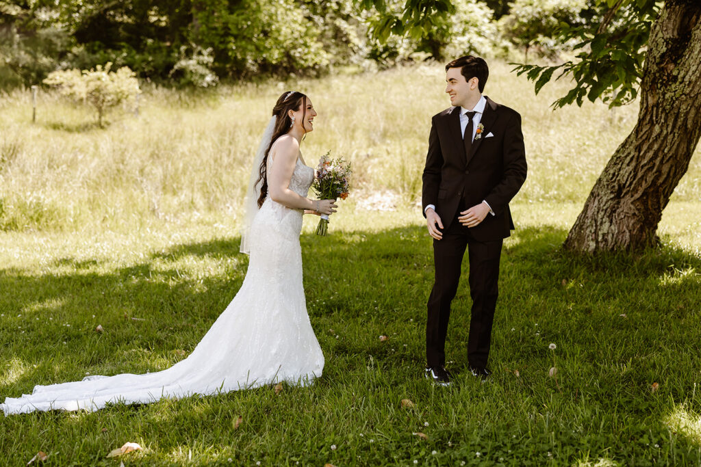 bride and groom elopement first look in a lush green field