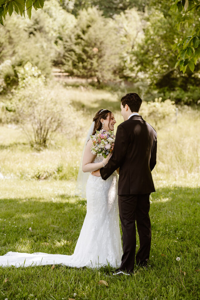 bride and groom elopement first look in a lush green field