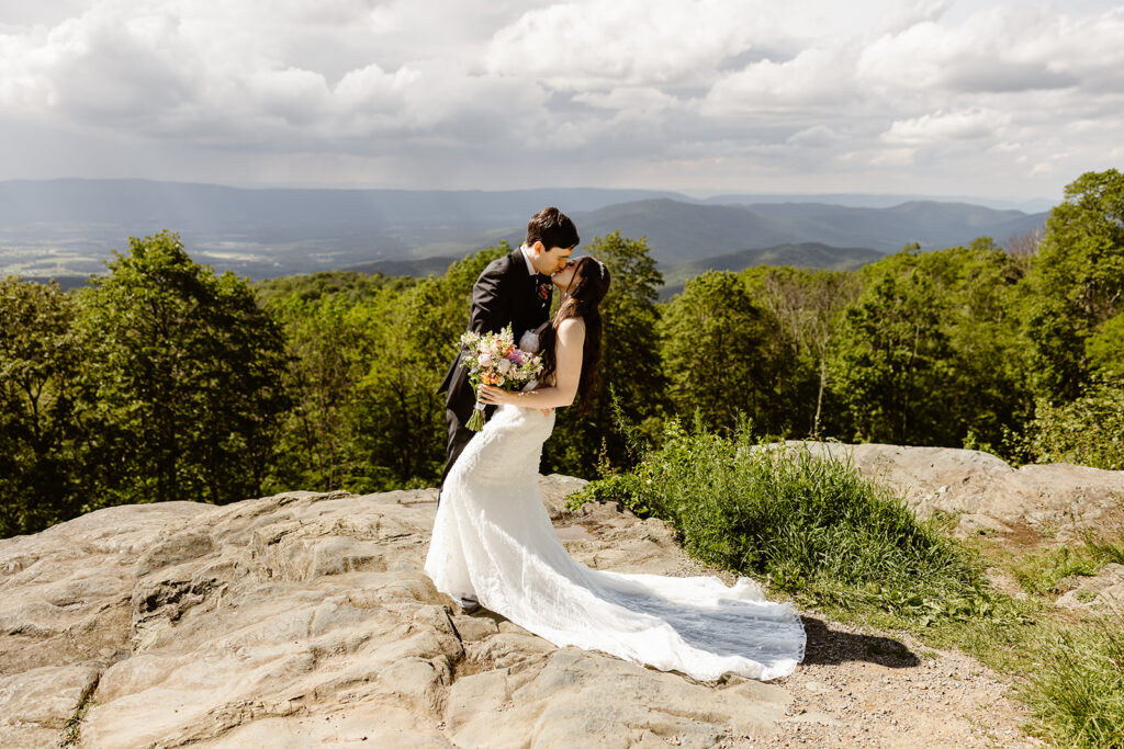 elopement couple kissing at a mountain overlook during their summer elopement in shenandoah
