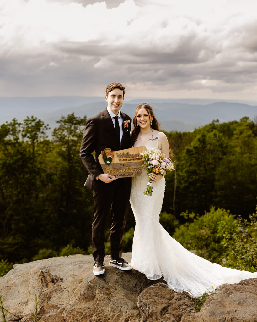 elopement couple with a "just eloped" sign at a mountain overlook during their summer elopement in shenandoah