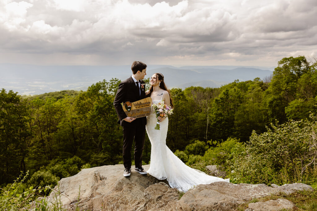 elopement couple with a "just eloped" sign at a mountain overlook during their summer elopement in shenandoah