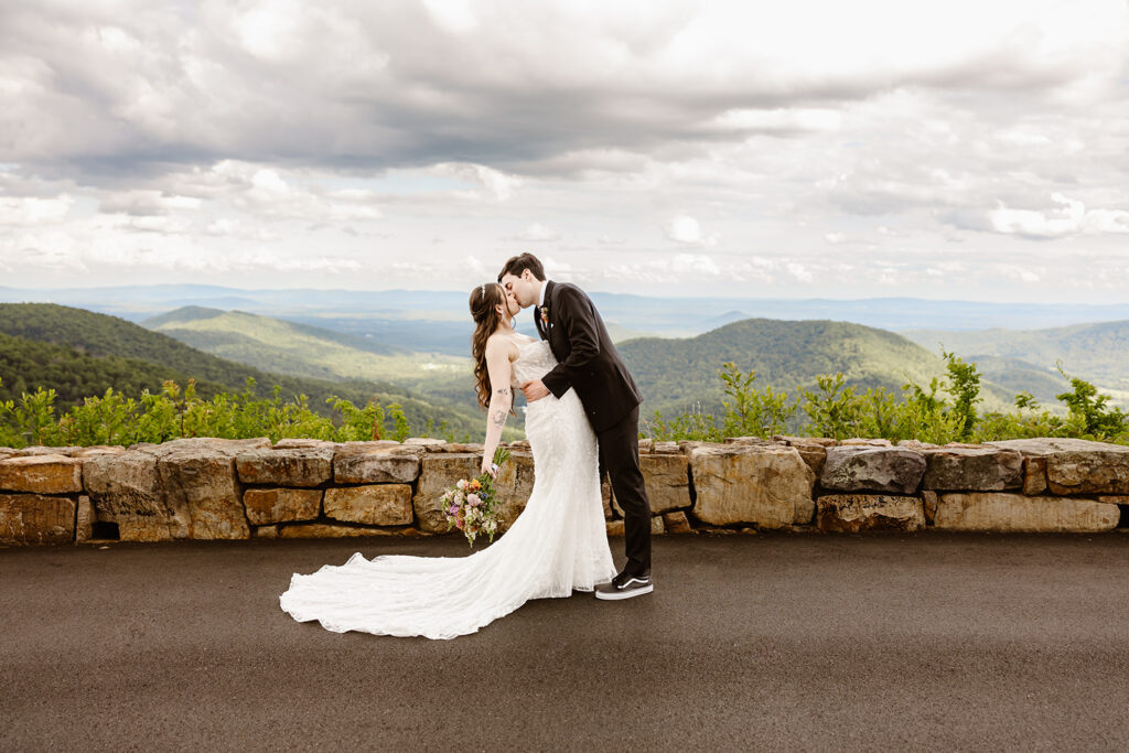 elopement couple kissing at a mountain overlook during their summer elopement in shenandoah